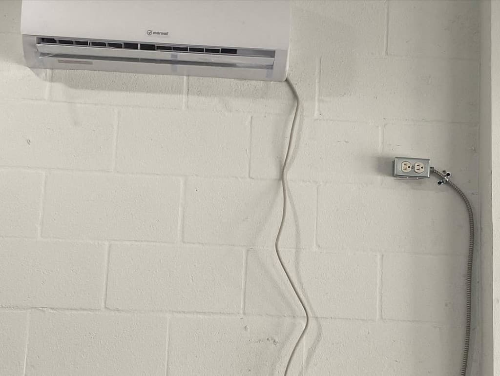 White Everwell ductless indoor unit cinderblock wall conduit box armored cable raceway disciplined electrical installation.